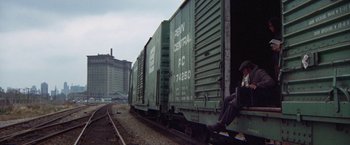 Movie still from “Scarecrow” (1973), directed by Jerry Schatzberg – A man sitting on the side of a train car; Wide shot, High angle