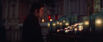 Movie still from “Scarecrow” (1973), directed by Jerry Schatzberg – A man standing in front of a bunch of lit candles; Medium shot, Low angle