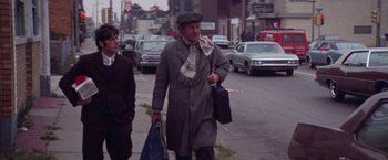 Movie still from “Scarecrow” (1973), directed by Jerry Schatzberg – A man walking down the street holding a bag of luggage; Medium shot, Low angle