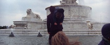 Movie still from “Scarecrow” (1973), directed by Jerry Schatzberg – A woman and a child are standing in front of a fountain; Wide shot, Low angle