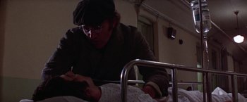 Movie still from “Scarecrow” (1973), directed by Jerry Schatzberg – A man in glasses and a hat looking down at a baby in a hospital bed; Close Up shot, Over the shoulder angle