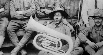 Movie still from “School Daze” (1988), directed by Spike Lee – An old photo of a man holding a tuba; Close Up shot, High angle
