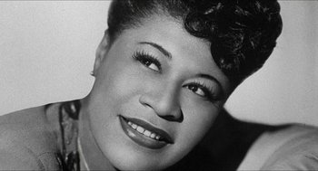 Movie still from “School Daze” (1988), directed by Spike Lee – A black and white photo of a woman smiling; Close Up shot, Low angle