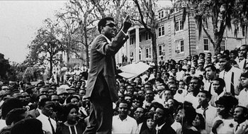 Movie still from “School Daze” (1988), directed by Spike Lee – A black and white photo of a man speaking to a crowd of people; Medium shot, High angle