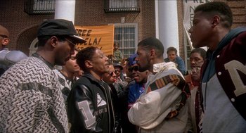 Movie still from “School Daze” (1988), directed by Spike Lee – A group of people standing next to each other on the street; Medium shot, Low angle