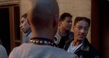 Movie still from “School Daze” (1988), directed by Spike Lee – A group of men standing next to each other in front of a wall; Close Up shot, Over the shoulder angle