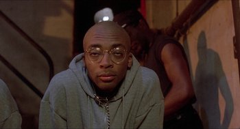 Movie still from “School Daze” (1988), directed by Spike Lee – A person wearing glasses and a hoodie; Close Up shot, Low angle
