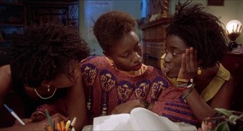 Movie still from “School Daze” (1988), directed by Spike Lee – A group of people sitting on top of a table; Medium shot, High angle