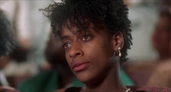 Movie still from “School Daze” (1988), directed by Spike Lee – A person wearing a necklace; Close Up shot, Low angle