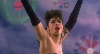 Movie still from “School Daze” (1988), directed by Spike Lee – A woman in a black dress with her arms up; Close Up shot, Low angle