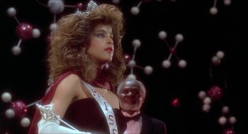 Movie still from “School Daze” (1988), directed by Spike Lee – A woman in a red dress is standing next to an older man; Medium shot, Low angle