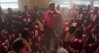 Movie still from “School Daze” (1988), directed by Spike Lee – A group of football players gathered in a room; Medium shot, Low angle