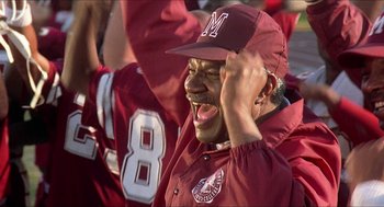 Movie still from “School Daze” (1988), directed by Spike Lee – A man in a maroon baseball uniform is laughing and holding his hands up in front of his face; Close Up shot, Low angle