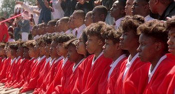 Movie still from “School Daze” (1988), directed by Spike Lee – A group of young men in red robes standing in a row; Medium shot, High angle