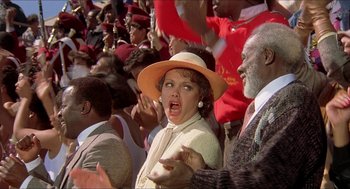 Movie still from “School Daze” (1988), directed by Spike Lee – A woman in a hat is in a crowd of people; Close Up shot, Low angle