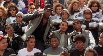 Movie still from “School Daze” (1988), directed by Spike Lee – A group of young men and women sitting in a stadium; Medium shot, High angle