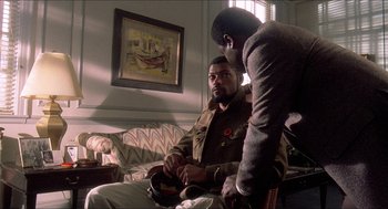 Movie still from “School Daze” (1988), directed by Spike Lee – Two men are sitting in a living room and one is holding a steering wheel; Medium shot, Over the shoulder angle