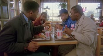 Movie still from “School Daze” (1988), directed by Spike Lee – A group of men sitting at a table eating food; Medium shot, High angle