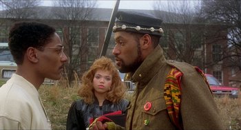 Movie still from “School Daze” (1988), directed by Spike Lee – A man and a woman standing next to each other in a field; Medium shot, Over the shoulder angle