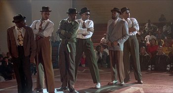 Movie still from “School Daze” (1988), directed by Spike Lee – A group of men standing next to each other on a stage; Wide shot, Low angle