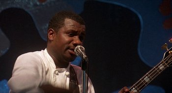 Movie still from “School Daze” (1988), directed by Spike Lee – A man in a white dress shirt and tie is holding a microphone; Close Up shot, Low angle