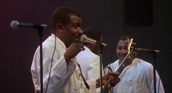 Movie still from “School Daze” (1988), directed by Spike Lee – A group of people that are playing music together; Medium shot, Low angle
