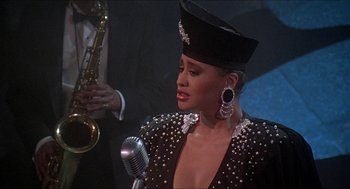 Movie still from “School Daze” (1988), directed by Spike Lee – A woman wearing a hat and a microphone; Close Up shot, Over the shoulder angle
