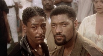 Movie still from “School Daze” (1988), directed by Spike Lee – Two black men standing next to each other in front of a crowd; Close Up shot, Low angle