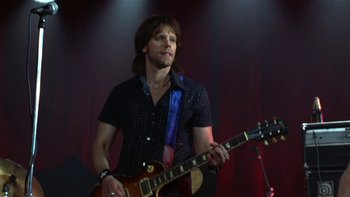 Movie still from “School of Rock” (2003), directed by Richard Linklater – A man in a black shirt is playing a guitar; Medium shot, Low angle