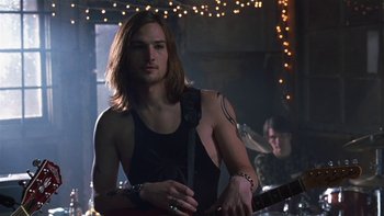 Movie still from “School of Rock” (2003), directed by Richard Linklater – A man with long brown hair holding a guitar; Medium shot, Low angle