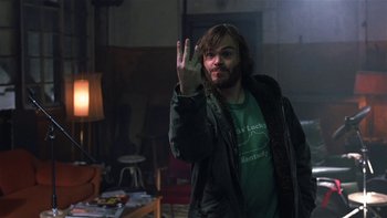 Movie still from “School of Rock” (2003), directed by Richard Linklater – A man in a green shirt is holding his hand up in the air; Close Up shot, High angle