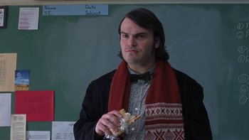 Movie still from “School of Rock” (2003), directed by Richard Linklater – A man wearing a scarf and holding a piece of food; Medium shot, Over the shoulder angle