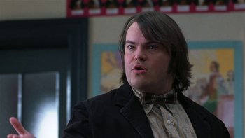 Movie still from “School of Rock” (2003), directed by Richard Linklater – A man with long hair wearing a suit and a bow tie; Close Up shot, Low angle