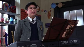 Movie still from “School of Rock” (2003), directed by Richard Linklater – A boy in a school uniform standing in front of a piano; Medium shot, Low angle
