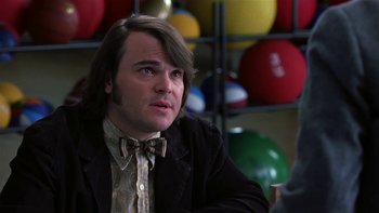 Movie still from “School of Rock” (2003), directed by Richard Linklater – A man with long brown hair wearing a bow tie; Close Up shot, Over the shoulder angle
