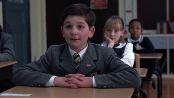 Movie still from “School of Rock” (2003), directed by Richard Linklater – A boy in a school uniform sitting in front of a table; Medium shot, Low angle