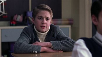 Movie still from “School of Rock” (2003), directed by Richard Linklater – A young man sitting at a table with his arms crossed; Close Up shot, Over the shoulder angle