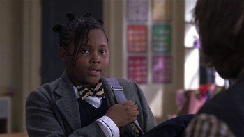 Movie still from “School of Rock” (2003), directed by Richard Linklater – A young boy in a suit and bow tie holding a backpack; Close Up shot, High angle