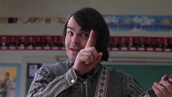 Movie still from “School of Rock” (2003), directed by Richard Linklater – A man with long black hair is pointing to his face; Close Up shot, Low angle