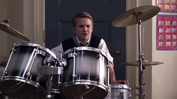 Movie still from “School of Rock” (2003), directed by Richard Linklater – A young boy is playing the drums in front of a door; Close Up shot, Low angle