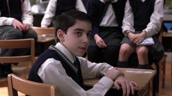 Movie still from “School of Rock” (2003), directed by Richard Linklater – A young boy sitting at a desk in front of other students; Medium shot, High angle