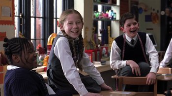 Movie still from “School of Rock” (2003), directed by Richard Linklater – A girl sitting at a table with a boy sitting at a desk; Medium shot, Low angle