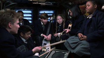 Movie still from “School of Rock” (2003), directed by Richard Linklater – A group of people sitting on a bus playing instruments; Medium shot, High angle