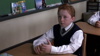 Movie still from “School of Rock” (2003), directed by Richard Linklater – A boy sitting at a table in front of a chalkboard; Medium shot, High angle