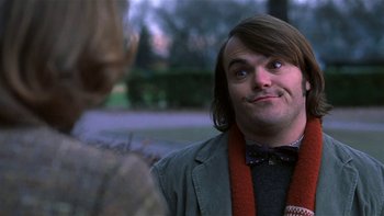 Movie still from “School of Rock” (2003), directed by Richard Linklater – A man with long brown hair wearing a jacket and a bow tie; Close Up shot, Over the shoulder angle