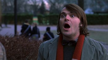 Movie still from “School of Rock” (2003), directed by Richard Linklater – A man with long brown hair wearing a gray jacket and a red scarf; Close Up shot, Low angle