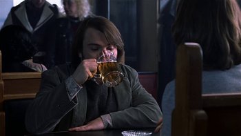 Movie still from “School of Rock” (2003), directed by Richard Linklater – A man sitting at a table with a glass of beer; Medium shot, Over the shoulder angle