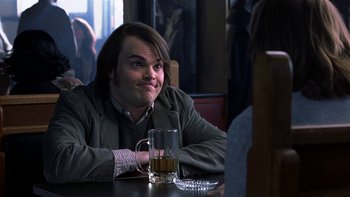 Movie still from “School of Rock” (2003), directed by Richard Linklater – A man sitting at a table with a glass of beer in front of him; Close Up shot, Over the shoulder angle