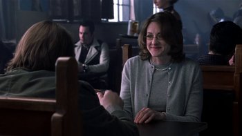 Movie still from “School of Rock” (2003), directed by Richard Linklater – A woman sitting at a table in front of a man holding a cell phone; Medium shot, Over the shoulder angle