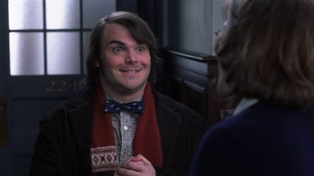 Movie still from “School of Rock” (2003), directed by Richard Linklater – A man wearing a bow tie talking to a woman; Medium shot, Over the shoulder angle